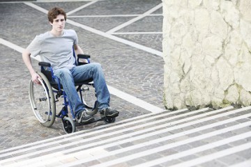 Junger Rollstuhlfahrer vor Treppen